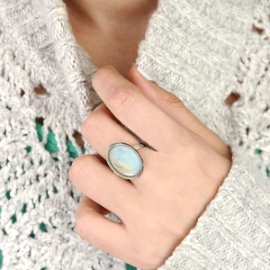 Vintage silver ring with oval moonstone gemstone worn on hand over a warm beige sweater