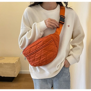 Detailed view of an orange quilted crossbody chest bag with adjustable strap and buckle