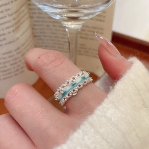 Close-up of elegant wavy silver ring with blue enamel inlay worn by a model