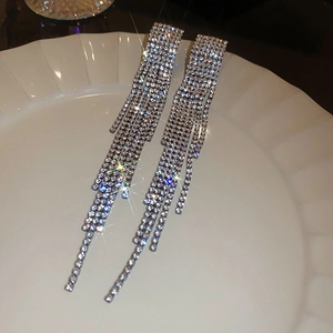 Elegant silver tassel earrings with sparkling rhinestones displayed on white porcelain