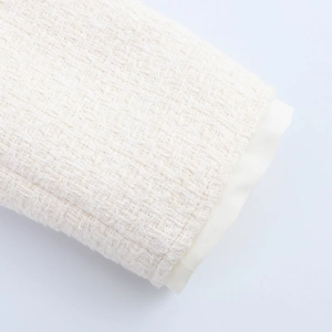 Close-up of cream-colored tweed fabric texture with thick weave and soft inner lining