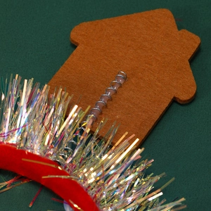 Détail d'un serre-tête de Noël avec une maison marron sur ressort et des paillettes
