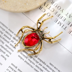 Detailed macro shot of a gold spider brooch with red gemstone on vintage book pages