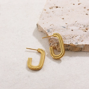 Macro shot of 18K gold plated hoop earrings featuring intricate woven texture on stone
