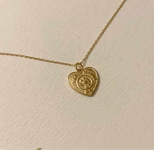 Detail of gold heart pendant necklace featuring yes maybe no spinning dial and arrow