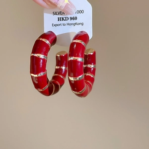 Macro shot of red enamel bamboo joint hoop earring with silver 1000 mark and golden stripes