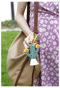 Detail of green cactus woven keychain with white tassels on a brown canvas bag