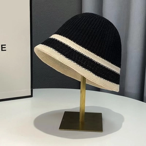 Chic black and white knitted bucket hat for women on a gold display stand