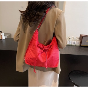 Detail of red suede tote bag featuring a decorative bow on shoulder strap with model