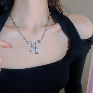 Detail view of silver safety pin necklace with double cross pendants on model neck