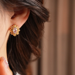 Gros plan d'une boucle d'oreille fleur vintage avec zircon violet sur l'oreille
