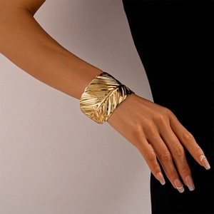 Detailed view of wide gold cuff bracelet featuring intricate metallic leaf texture and veins