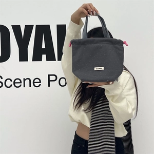 Dark grey wool-like polka dot drawstring tote bag featuring pink toggles and label