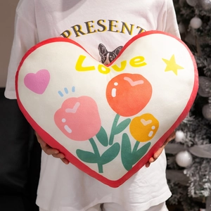 Plush heart-shaped throw pillow with tulip patterns and Love text held by a model