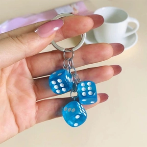 Close-up of translucent blue resin dice charms with white dots on a silver keychain