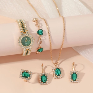 Elegant women's gold watch and jewelry set with emerald green stones and crystals