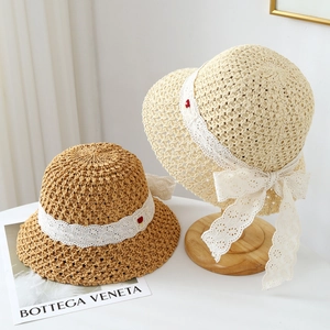 Handwoven straw sun hat with white lace ribbon bow and small red floral details