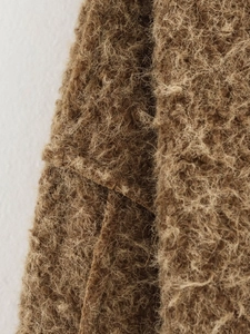 Macro detail of brown mohair cardigan fabric texture and soft fuzzy knit craftsmanship