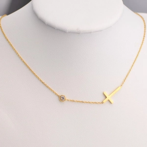 Gold chain necklace with horizontal cross and clear crystal zircon on a neck model