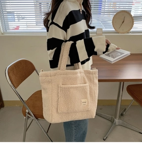 Detail view of cream white fleece tote bag with brand label and front square pocket