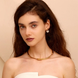 Detail of gold choker and bow heart earrings with pearls on a female model
