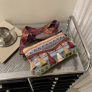 Close-up of bohemian woven bag with colorful geometric patterns and silk tassels