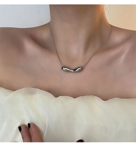 Macro detail of irregular fluid silver pendant on a sleek snake chain necklace