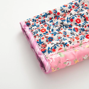 Détail du tissu matelassé à fleurs roses avec coutures précises et bordure rayée