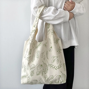 Detail of minimalist white canvas tote bag with green botanical leaf print pattern