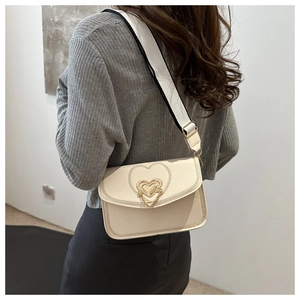 Detail of cream crossbody bag featuring golden heart lock and black-white wide strap