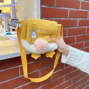 Detail of cute yellow lamb wool duck crossbody bag with pink pompom and strap