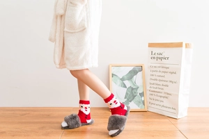 Close-up of cozy red Christmas crew socks featuring reindeer and Santa Claus patterns