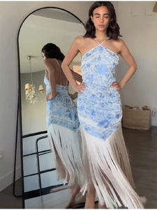 Detail of blue printed halter neck dress with long white fringe and open back design
