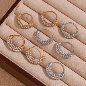 Detailed view of gold and silver hoop earrings with rhinestones and pearls in a jewelry box