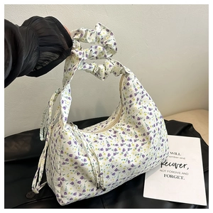 Detail of floral underarm bag with purple flower patterns and ruched handle grip