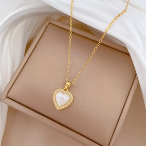 Close-up of golden heart pendant with mother-of-pearl and sparkling small crystals