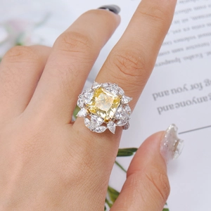 Close-up of yellow cushion-cut diamond ring with marquise halo on woman's hand