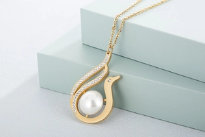 Close-up of golden swan pendant with white pearl and sparkling crystal accents