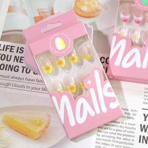 Short round French press-on nails with yellow frangipani flower designs in pink box