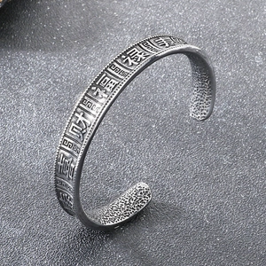 Close-up of vintage steel cuff featuring engraved Chinese fortune characters and texture