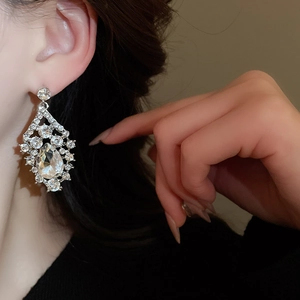 Detail view of model wearing vintage teardrop crystal earrings in silver finish