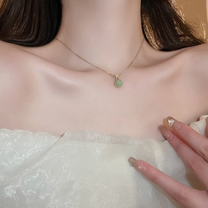Nahaufnahme einer eleganten Goldhalskette mit rundem grünem Jade-Anhänger am Hals