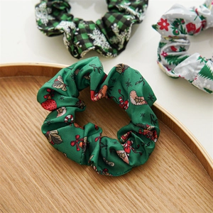 Detailed view of three festive Christmas fabric hair scrunchies on a round wooden tray