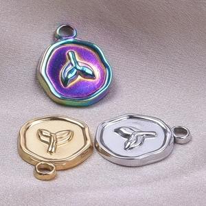 Macro detail of whale tail pendants in iridescent, gold, and silver finishes on silk