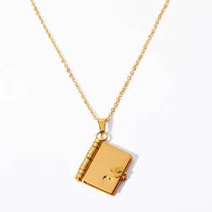 Detailed close-up of a gold book-shaped locket pendant with a delicate heart and hinge