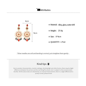 Détail de boucles d'oreilles ornées en alliage doré avec pierres rouges, noires et cristaux
