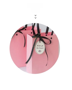 Pink gift bag detail with black ribbon bow and 'With all my heart' message tag