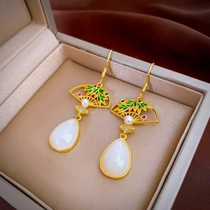 Dettaglio di orecchini a ventaglio d'oro con foglie di smalto e pendente di giada bianca