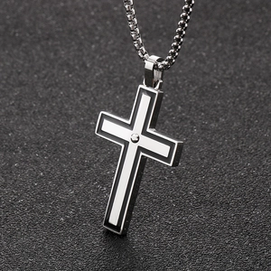 Close-up of a two-tone black and white cross pendant on a dark beaded metal chain