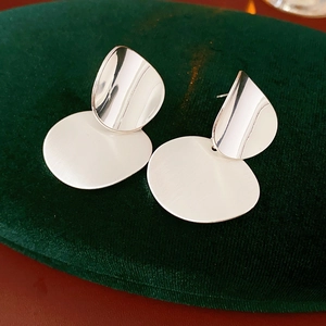 Macro shot of silver metal brushed oval earrings on a velvet jewelry box surface